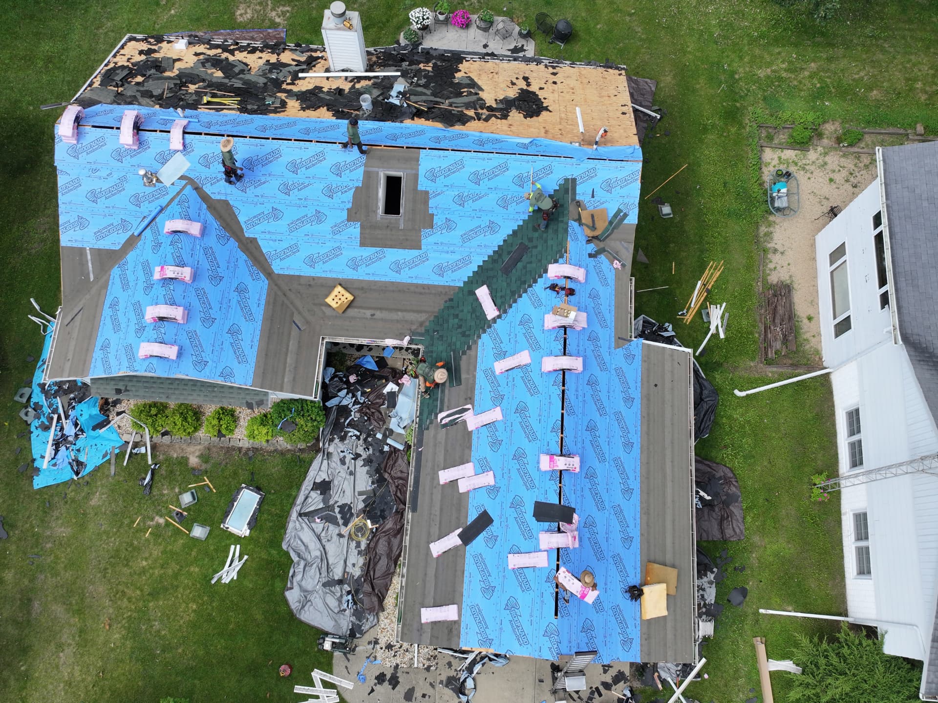 Drone photo of a Hammer It crew mid tear-off with synthetic underlayment installed on a two-story home