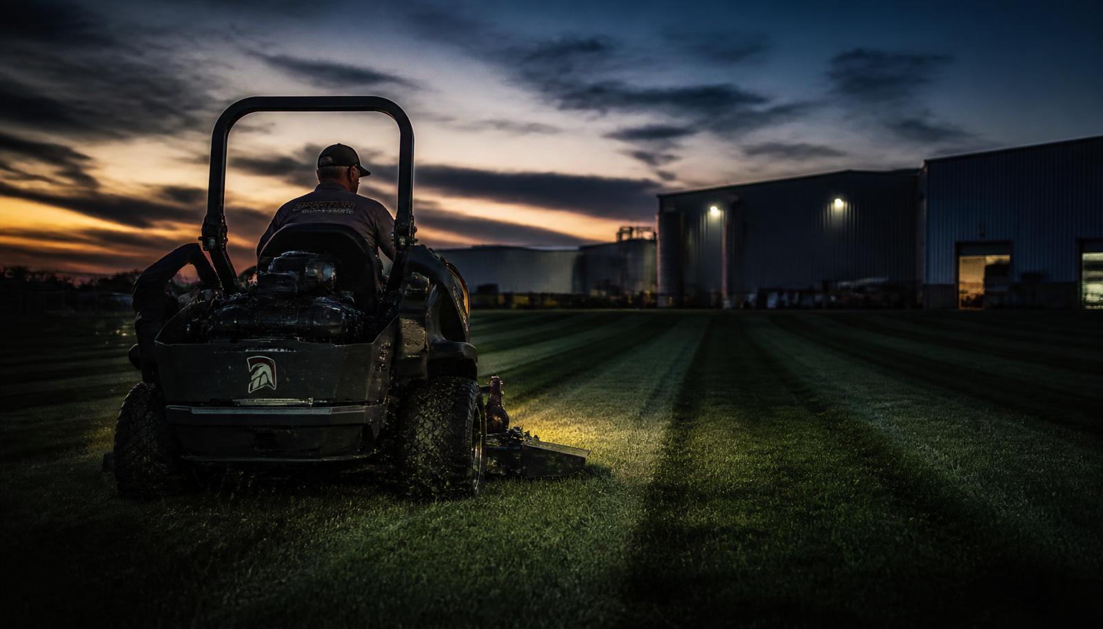 Commercial zero-turn mower cutting stripes into a large property lawn